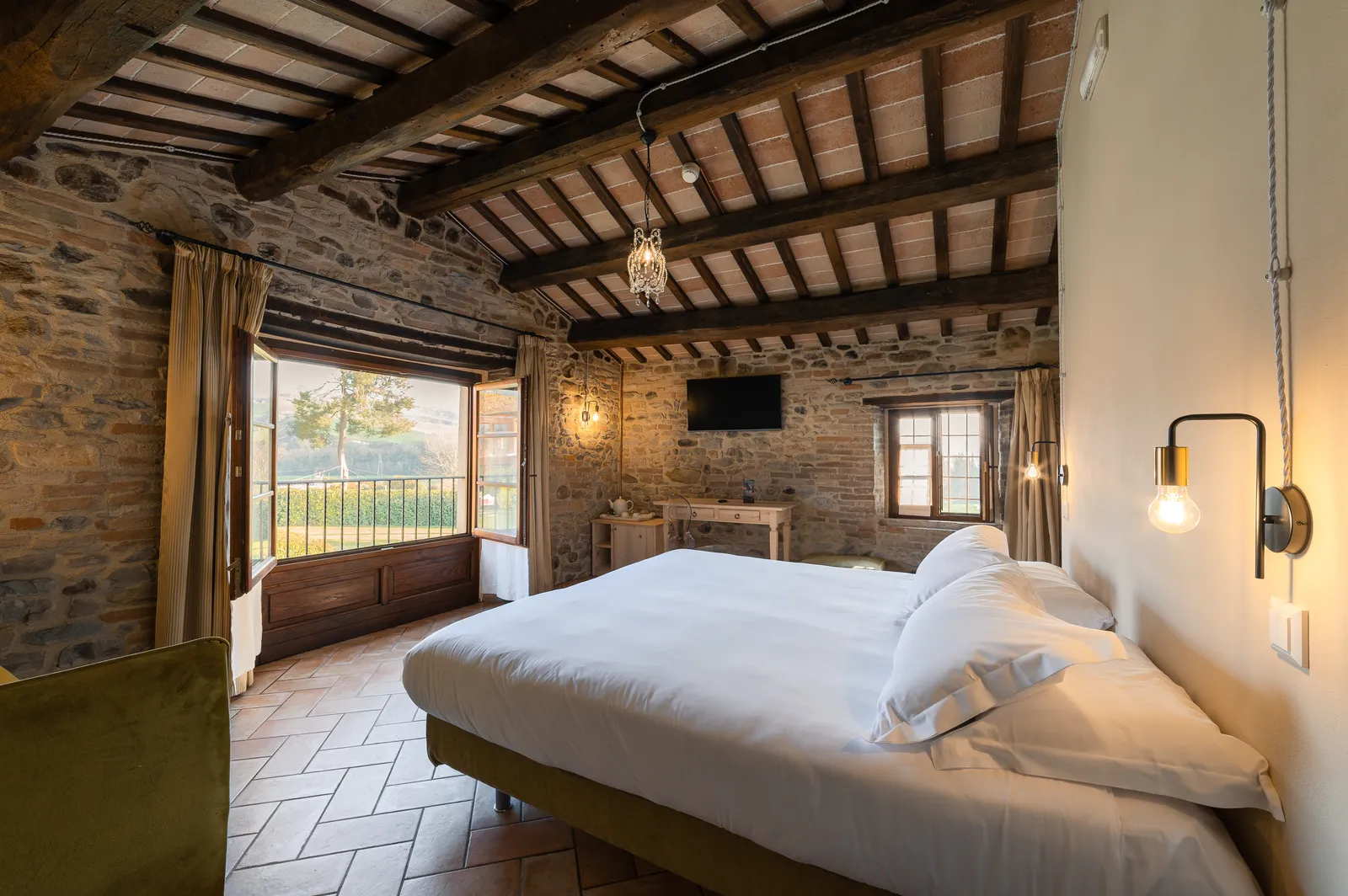 Suite Padronale J-Suite Granaio con letto matrimoniale, pareti in pietra a vista e ampia finestra sulle colline del Montefeltro