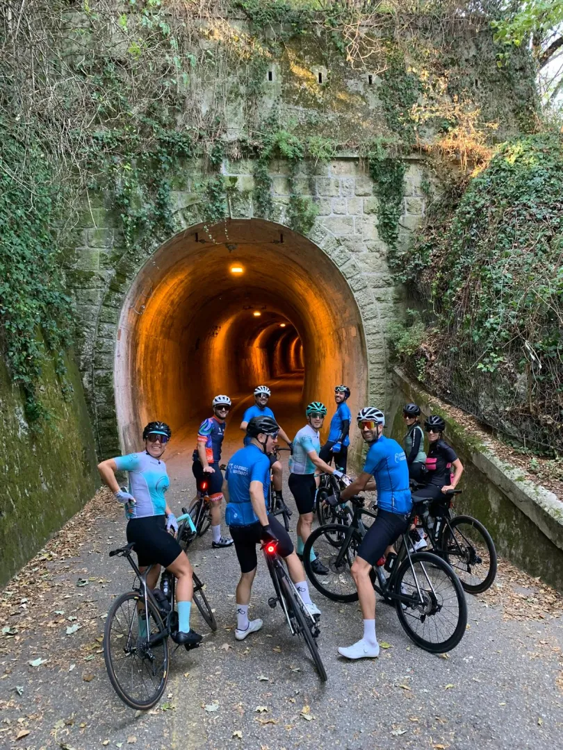 Gruppo di ciclisti in sosta all'imbocco di una galleria lungo un percorso del Montefeltro